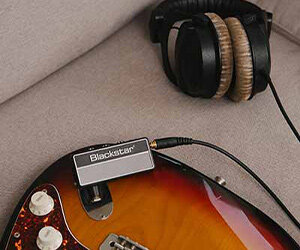 Blackstar amPlug2 FLY Kopfhörerverstärker, angeschlossen an eine E-Gitarre neben einem Paar Kopfhörer
