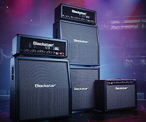 Gruppe von Blackstar Series One Gitarrenverstärkern auf der Bühne mit mehrfarbigen Lichtern dahinter
